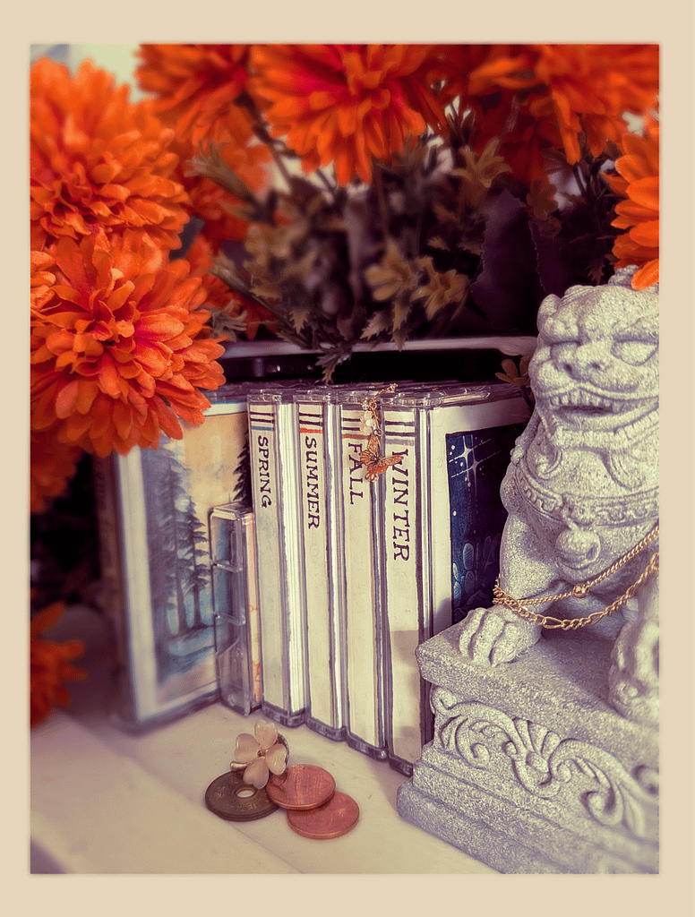 Large cassette collections grouped by spring, summer, fall, and winter. Flowers and a small stone lion bookend the cassettes.